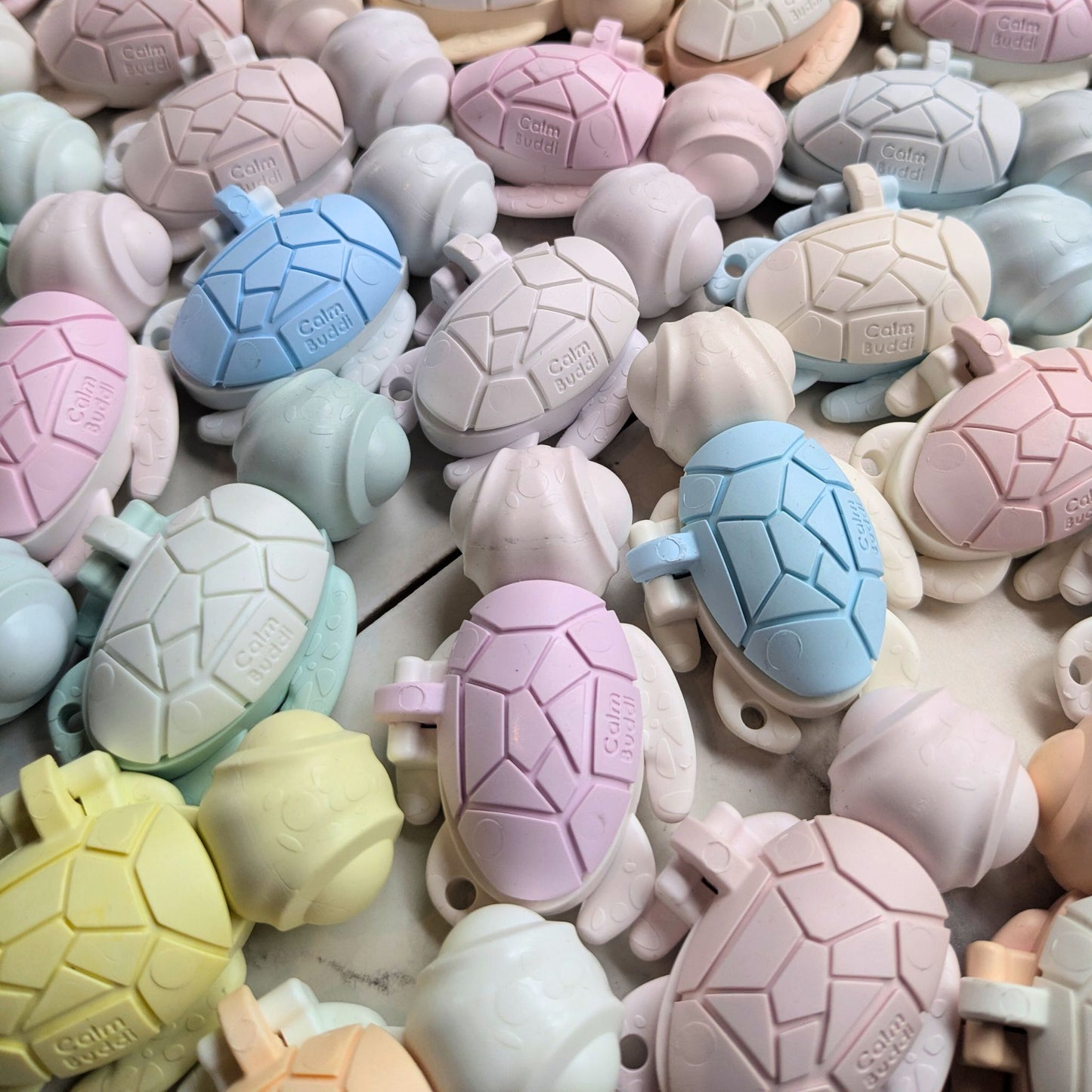 Assorted turtle-shaped adult fidget toys in pastel colors on a textured surface