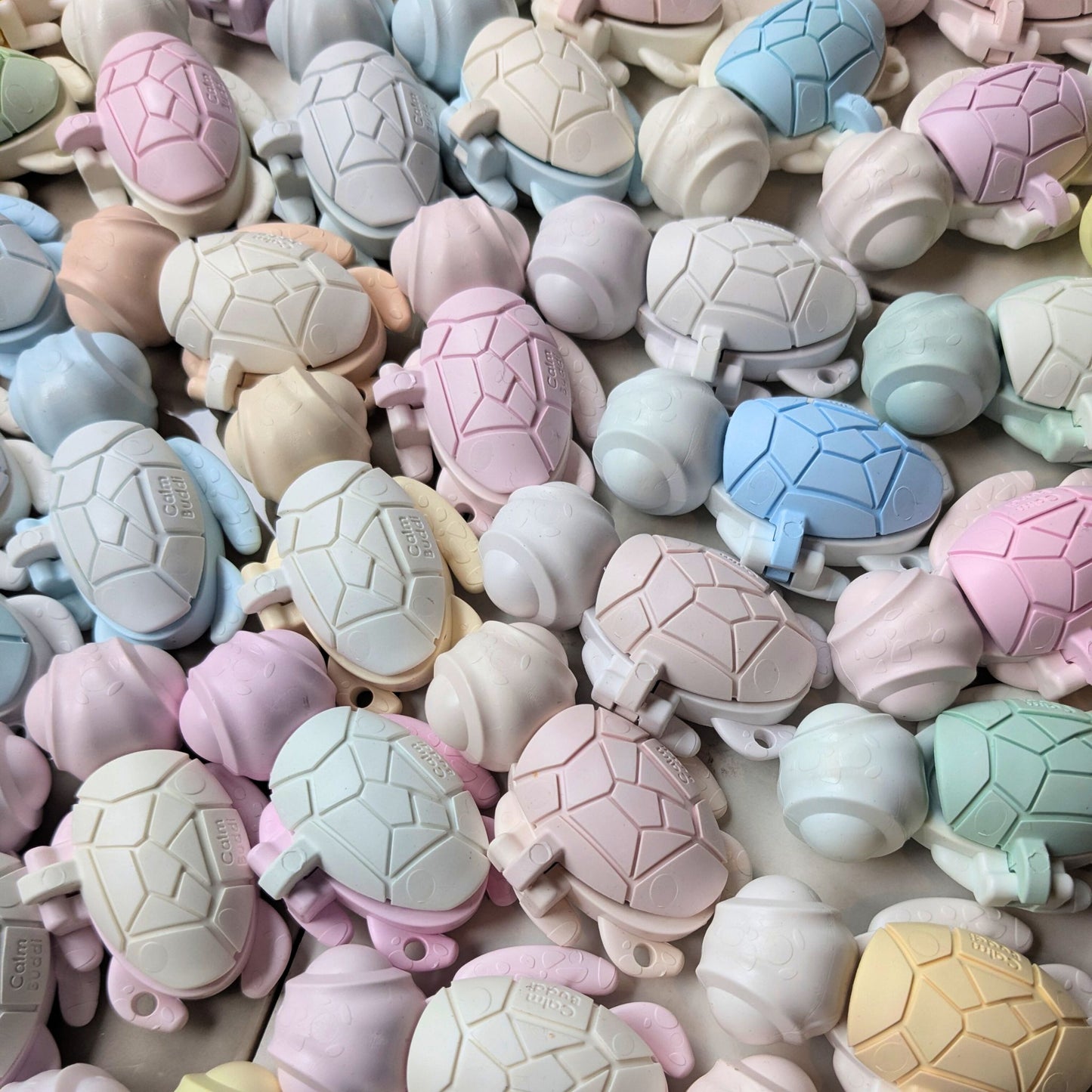 Assorted turtle-shaped adult fidget toys in pastel colors on a textured surface
