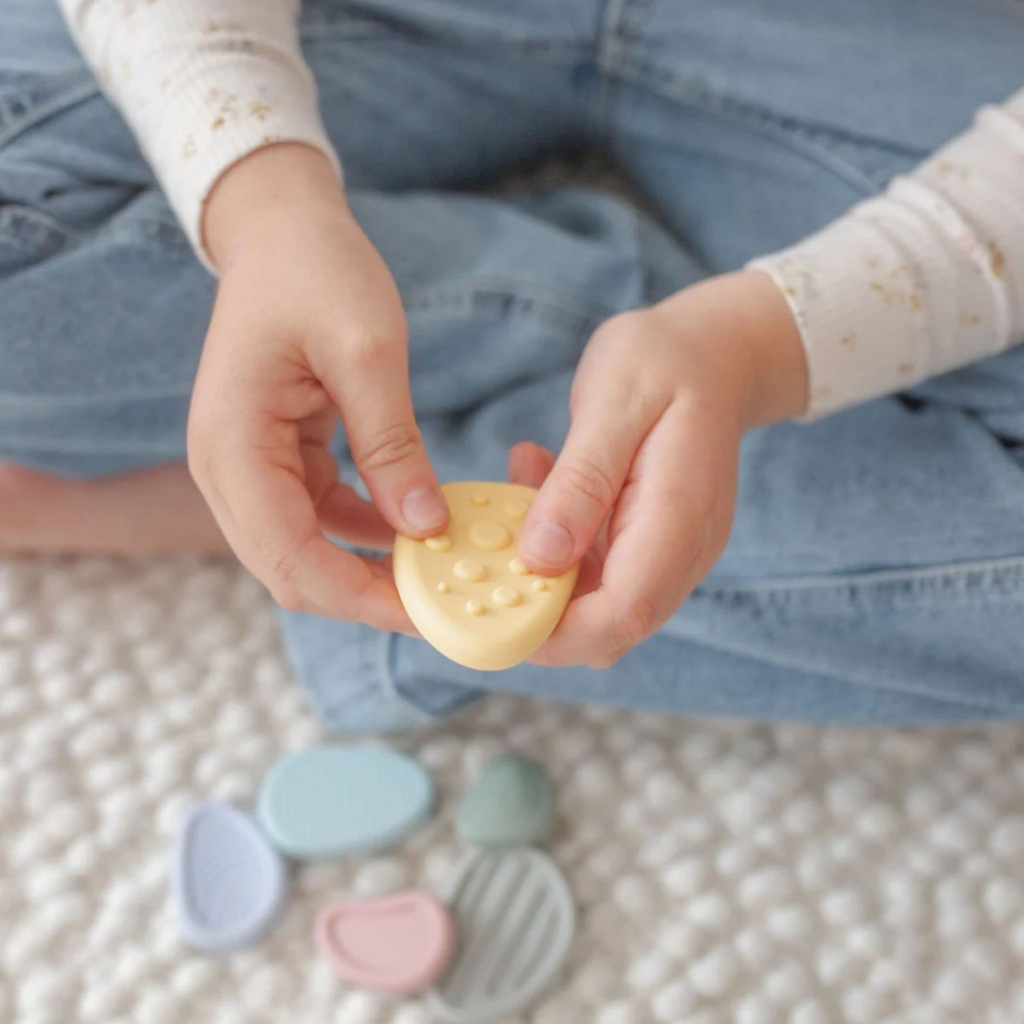 Child's hands holding textured silicone sensory worry stones .