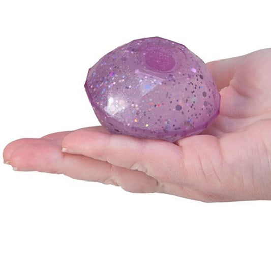Hand holding a purple NeeDoh Groovy Jewel diamond-shaped squishy ball with a glittery texture on a white background