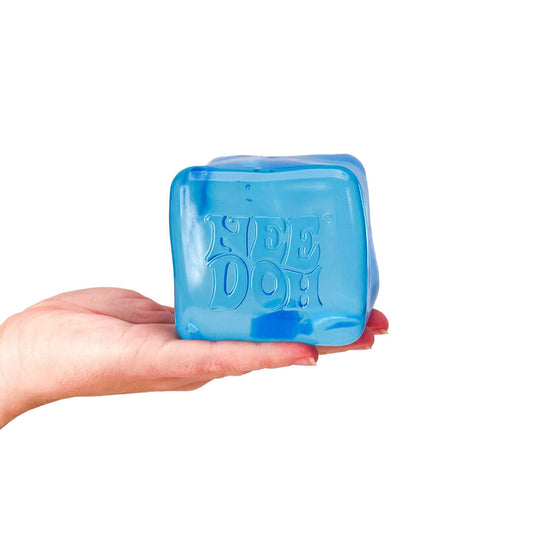 Hand holding a blue NeeDoh Niceberg ice cube squishy stress ball against a white background