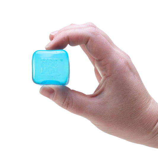 Hand holding a blue NeeDoh Teenie Nice Ice Baby ice cube squishy stress ball in packaging against a white background