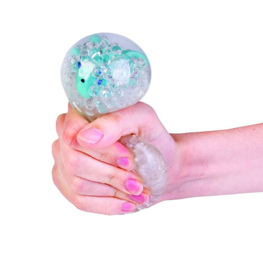 Hand holding a stress ball squishy with a blue axolotl toy inside on a white background