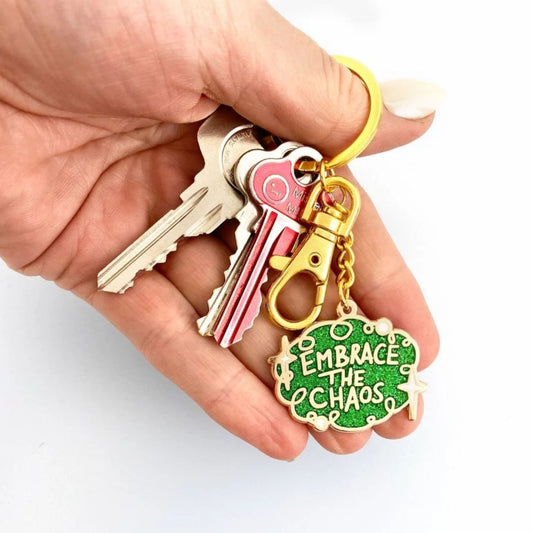 Hand holding a Jubly Umph Embrace the Chaos Keychain with keys