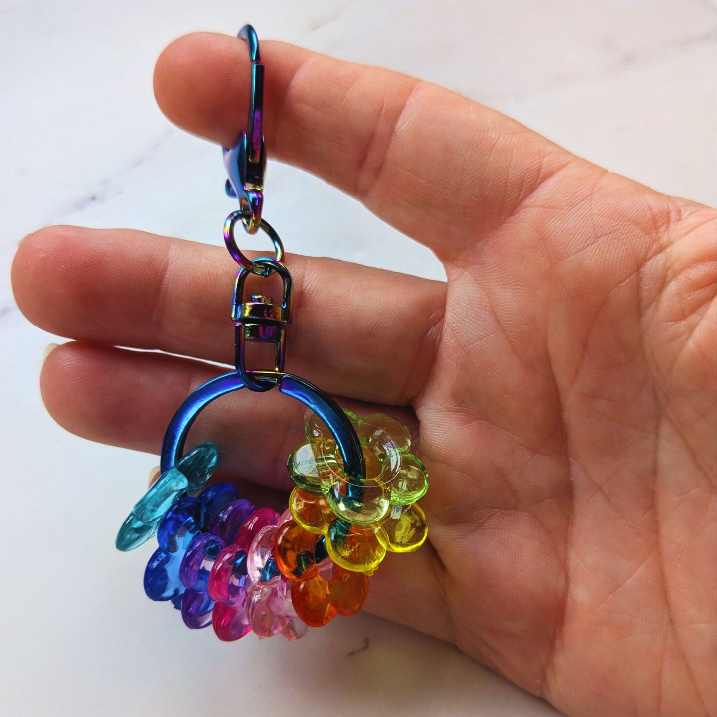 Hand holding Rainbow Drop Keychain Fidget Oil Slick with Rainbow Beads