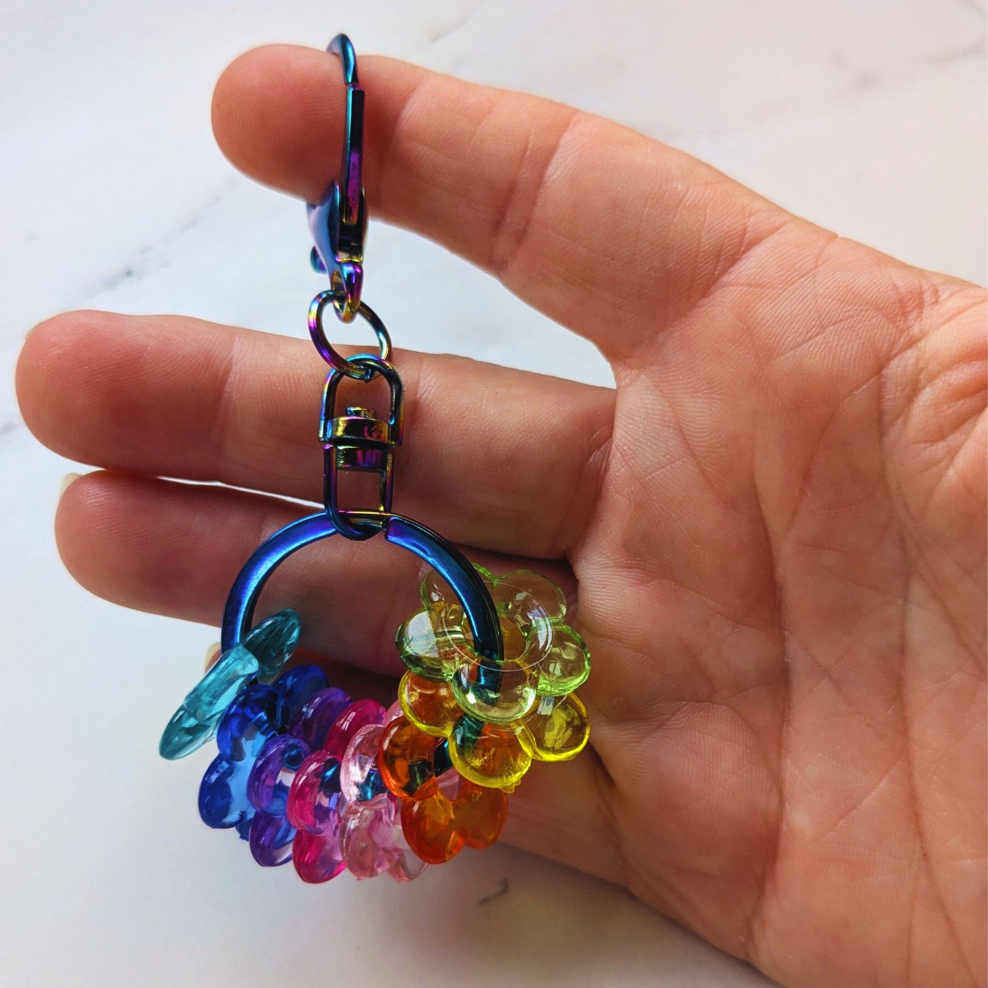 Hand holding Rainbow Drop Keychain Fidget Oil Slick with Rainbow Beads