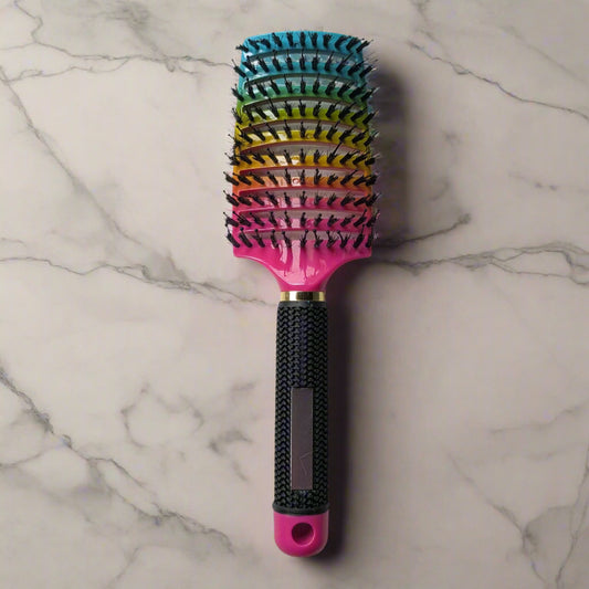 Multicolored hairbrush with a pink handle on a marble surface