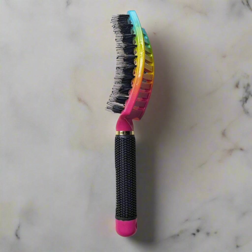 Multicolored pet brush with a textured handle on a marble floor