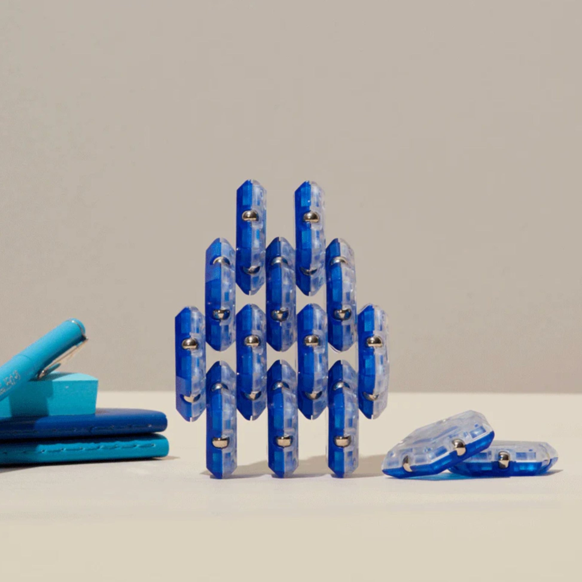 Blue Speks magnetic fidget in a geometric shape on a beige background