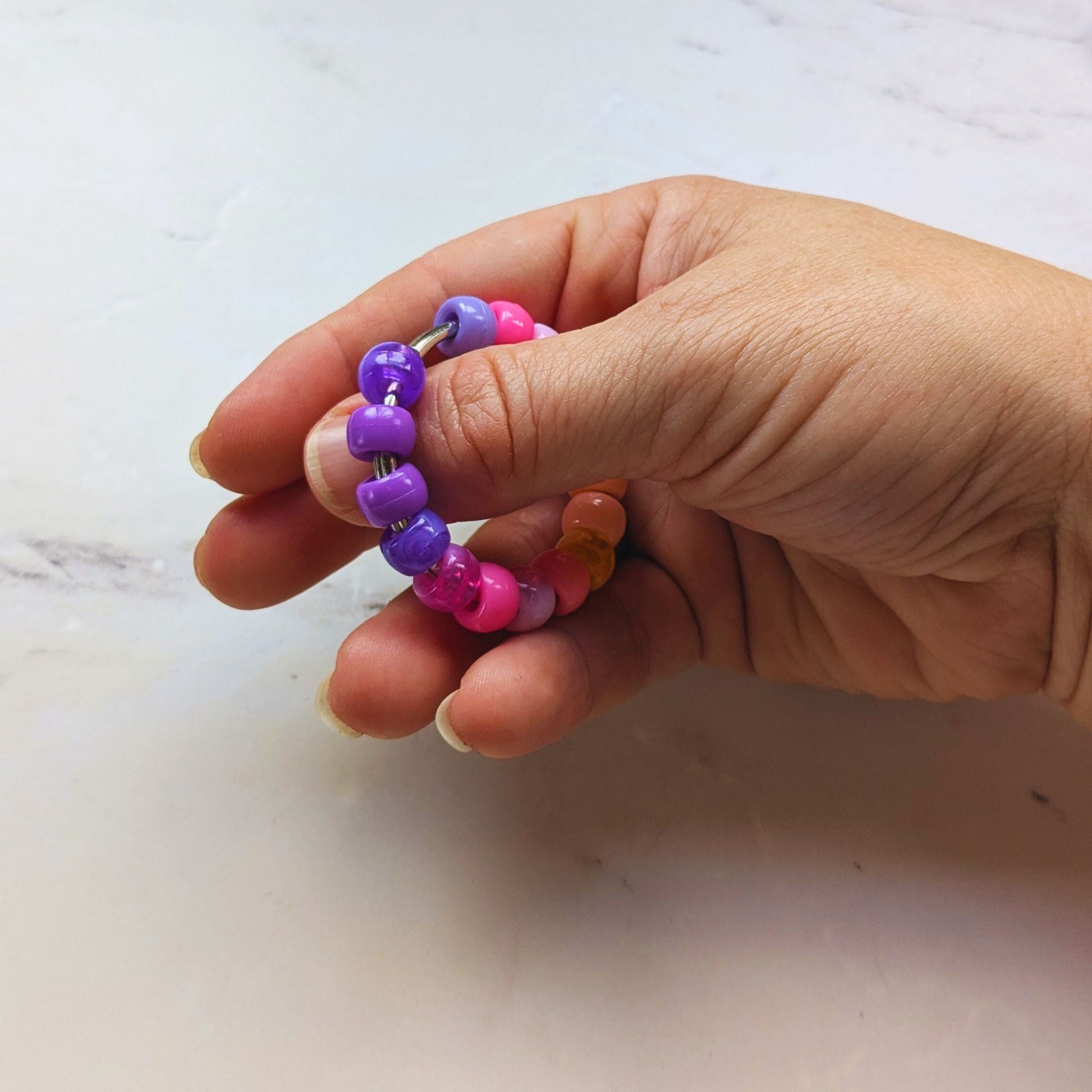 Hand holding Sunset Swirl Roller Fidget by Tutti Frutti Fidgets