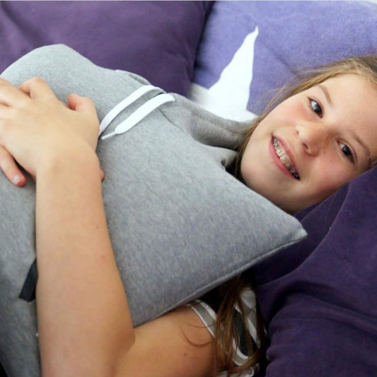Child using a grey hoodie-shaped vibrating cushion on a purple couch