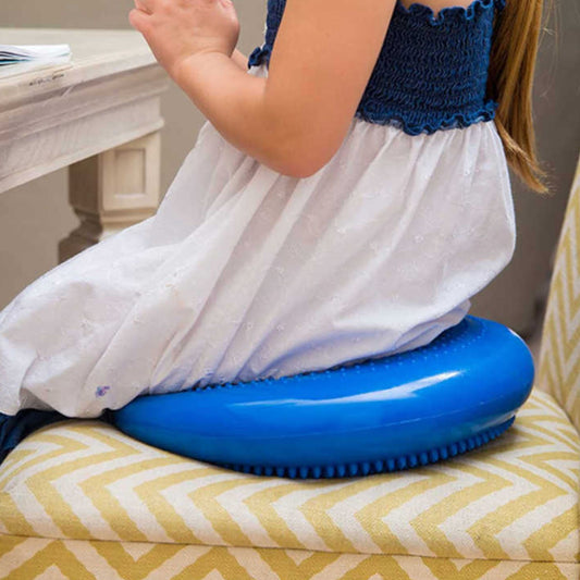 Child sitting on blue wobble balance cushion