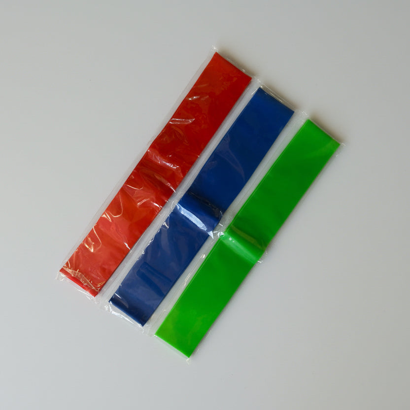 Three colourful fidget chair bands (red, blue, green) on a white surface.
