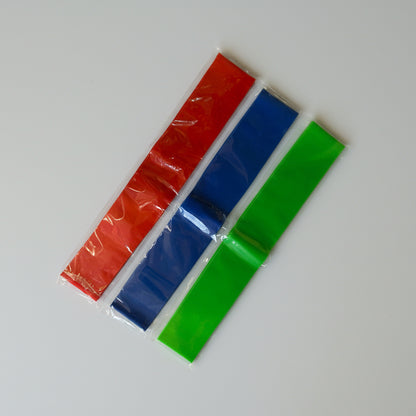 Three colourful fidget chair bands (red, blue, green) on a white surface.