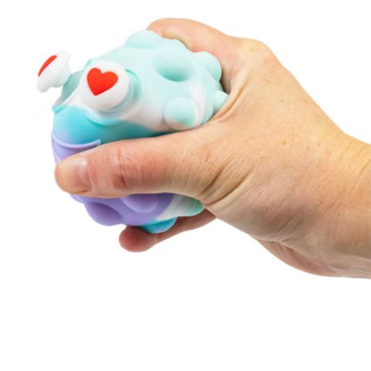Hand holding a colourful squishy toy with a heart on a white background