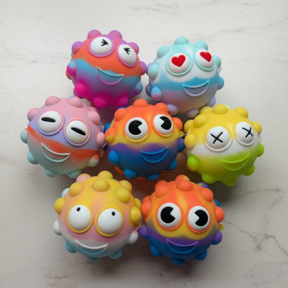 Colorful toy pop-it monster fidgets with various expressions on a light gray surface