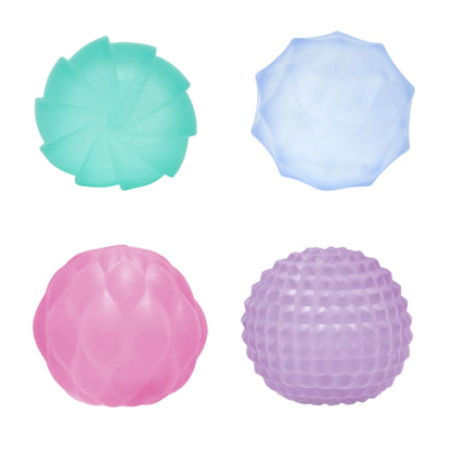Four textured stress balls arranged in a 2x2 grid on a white background: a mint green fan-shaped ball, a light blue faceted ball, a pink smooth ball, and a purple dimpled ball.