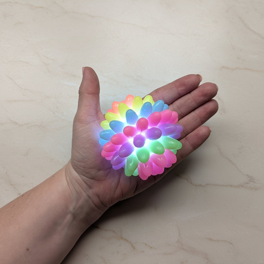 Hand holding a colourful ball on a plain background