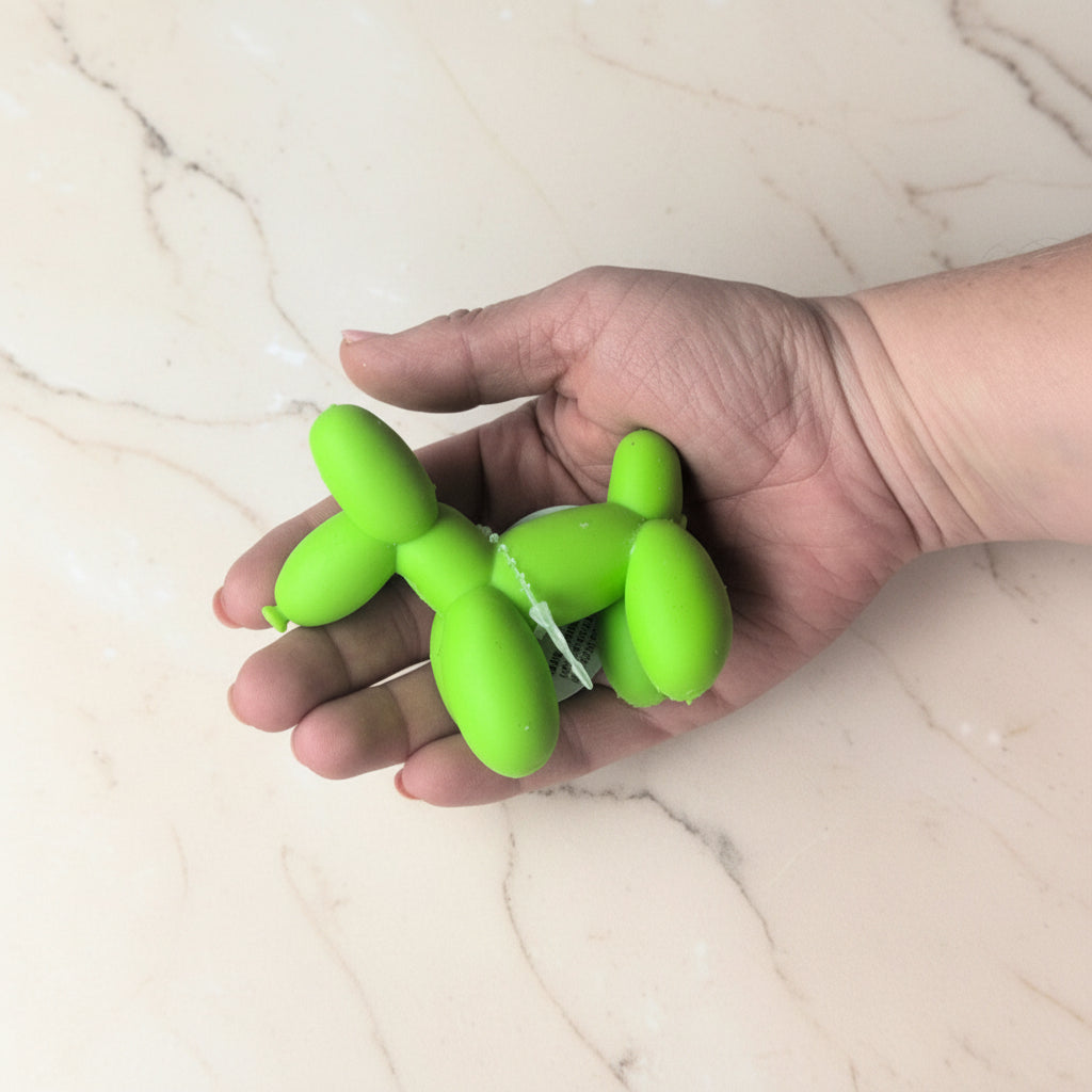 Hand holding a green balloon dog fidget toy on a light-coloured surface