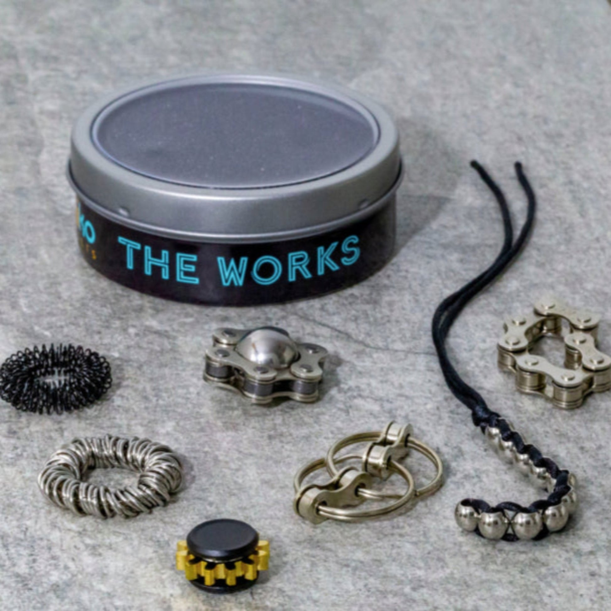 The Works Fidget Kit by Kaiko with seven fidgets and a display case in Black and Silver