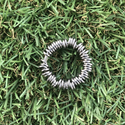 Silver metal adult fidget toy on green grass background
