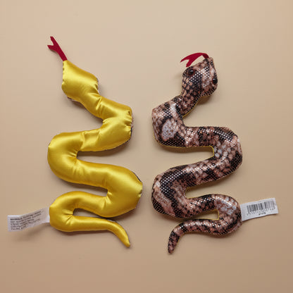 Two snake-shaped toys, one yellow and one with a pattern, on a light wooden surface.