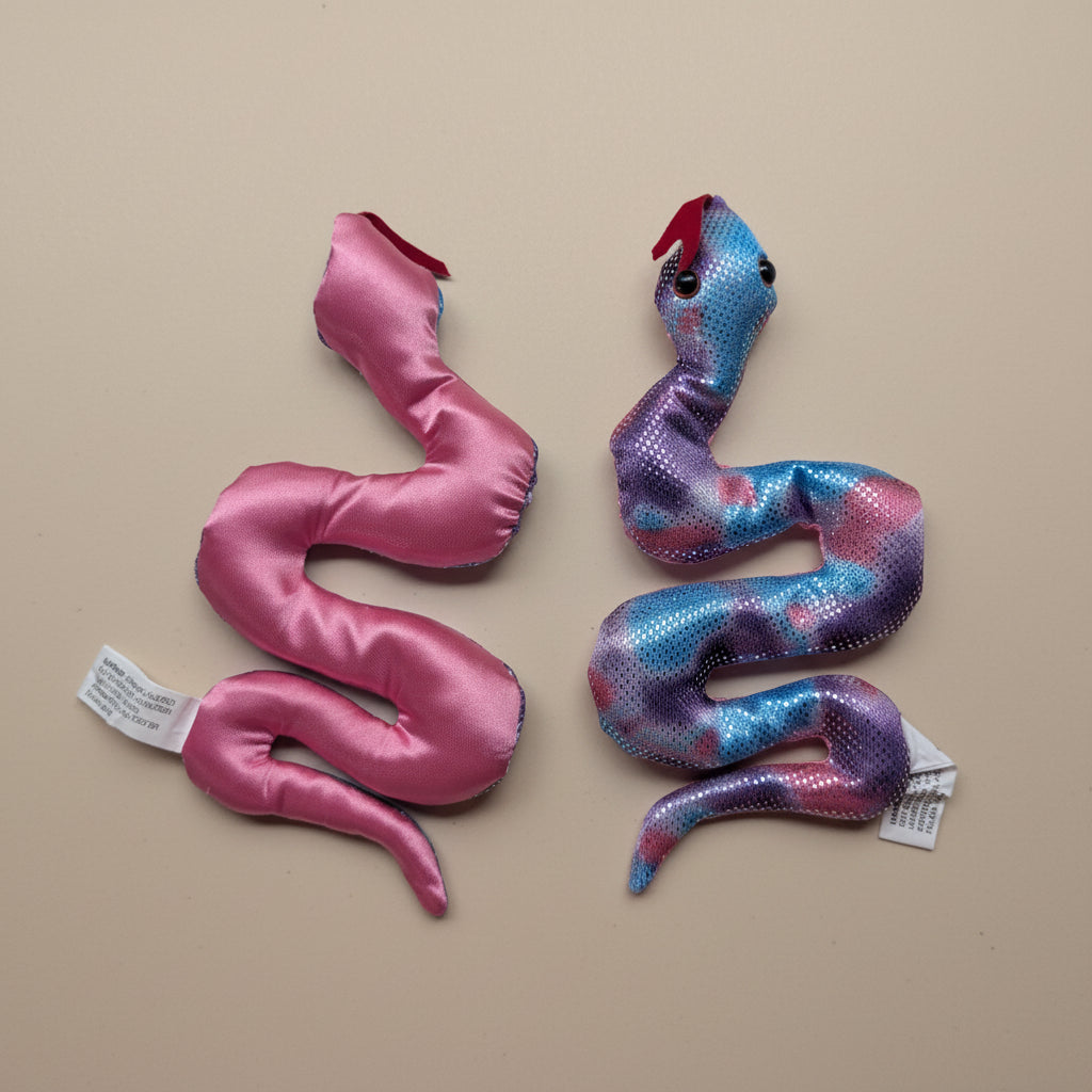 Two snake-shaped toys on a plain background with tags attached.