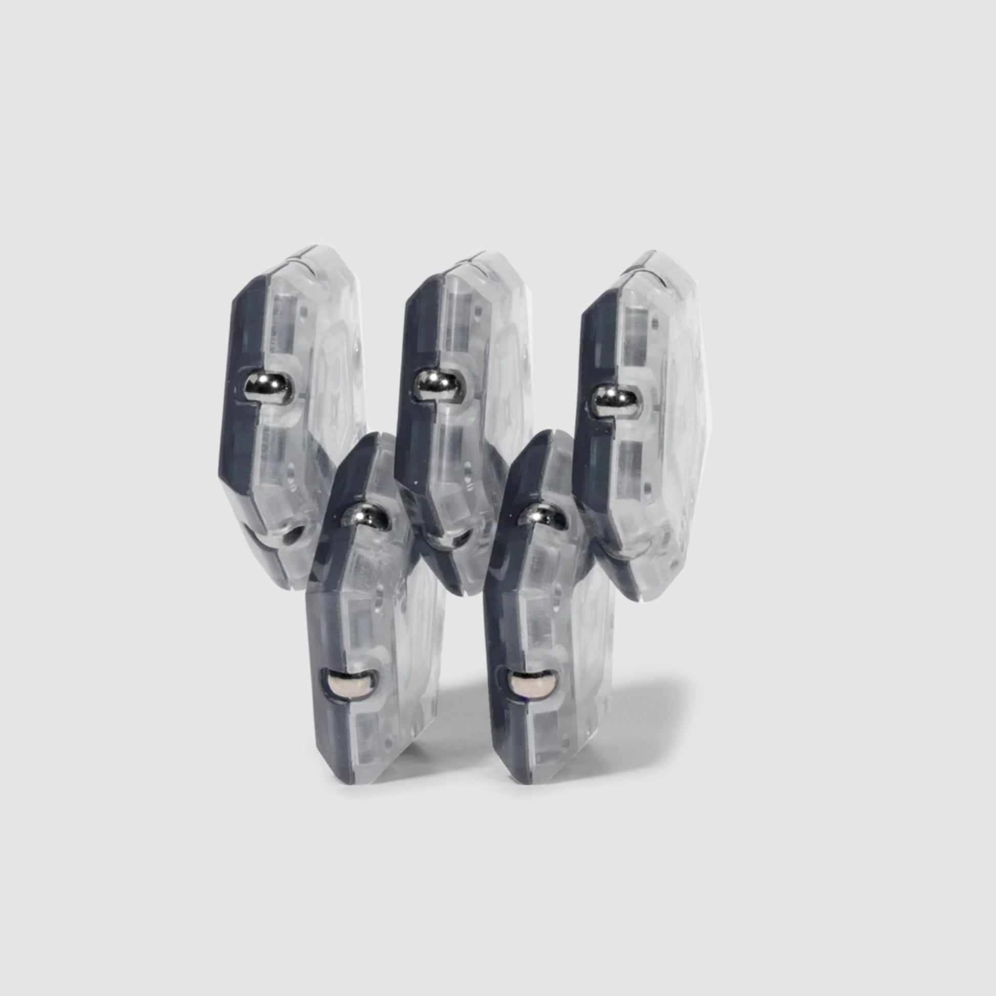 Set of five clear and grey Speks Geode magnetic fidget sphere pieces in a horizontal structure on a light grey background