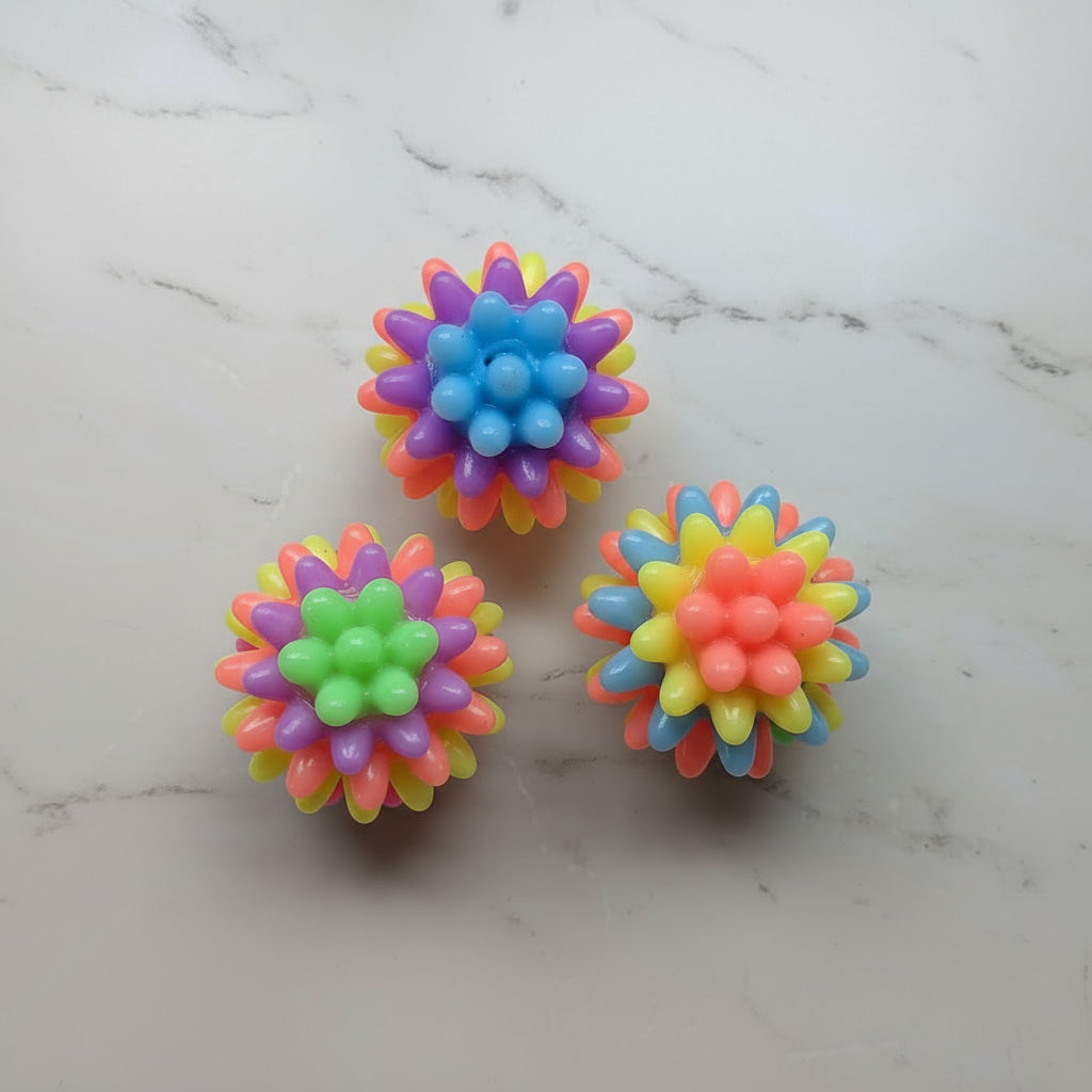 Three colorful rubber fidget balls on a plain surface