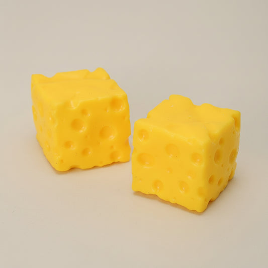 Two yellow cheese cube-shaped sqiushies on a beige background