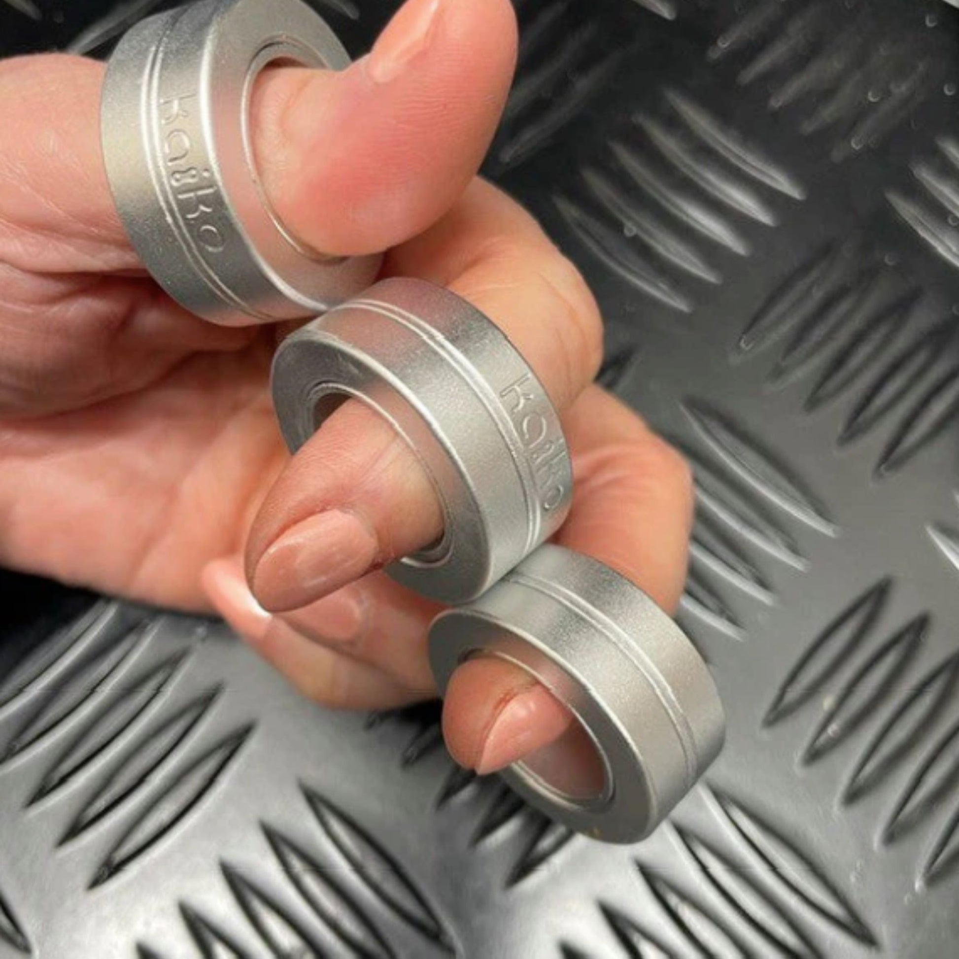 Hand holding Kaiko's Tri Magnetic Fidget Rings in a row