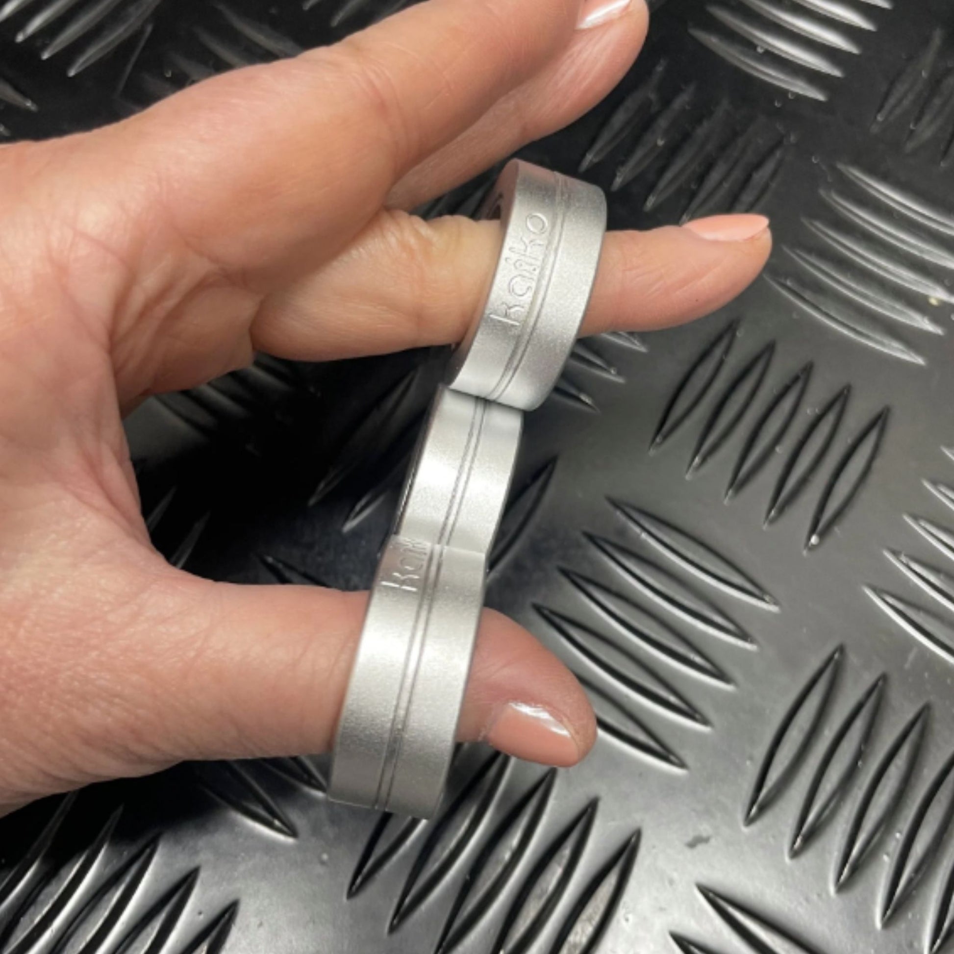 Hand holding Kaiko's Tri Magnetic Fidget Rings in a row of three